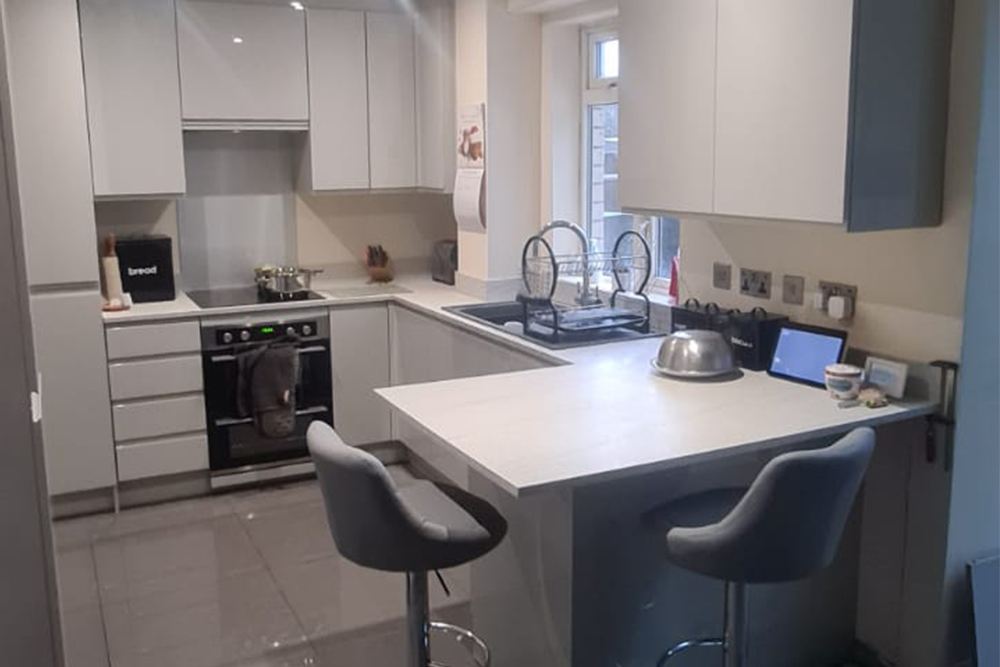 Kitchen refurbishment c/w gloss panelled cabinets and cupboards with large slate grey floor tiles